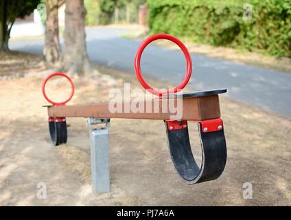 Eine Großaufnahme des leeren braunen Holz Hollywoodschaukel mit roten Ankern auf dem Spielplatz. Geringe Tiefenschärfe. Im Vordergrund standen. Stockfoto