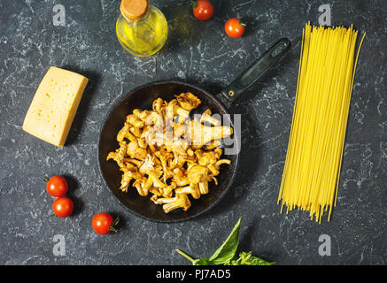 Teigwaren und Pfifferlingen Pilz auf dunklem Stein Hintergrund. Ansicht von oben. Stockfoto