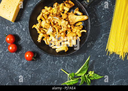 Teigwaren und Pfifferlingen Pilz auf dunklem Stein Hintergrund. Ansicht von oben. Stockfoto