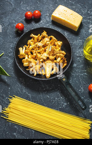 Teigwaren und Pfifferlingen Pilz auf dunklem Stein Hintergrund. Stockfoto