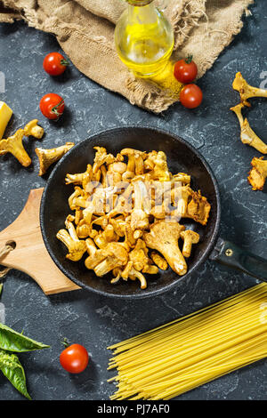Teigwaren und Pfifferlingen Pilz auf dunklem Stein Hintergrund. Ansicht von oben. Stockfoto
