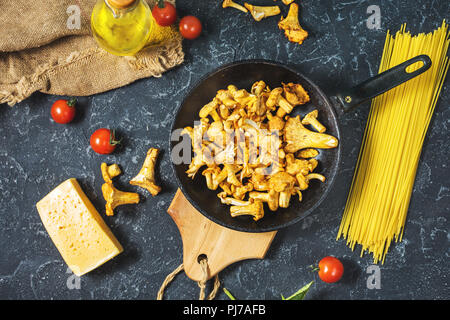 Teigwaren und Pfifferlingen Pilz auf dunklem Stein Hintergrund. Ansicht von oben. Stockfoto