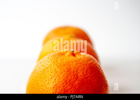 Drei Orangen Mandarinen hinter einander gesetzt. Flache Freiheitsgrad. Über weiß isoliert. Stockfoto