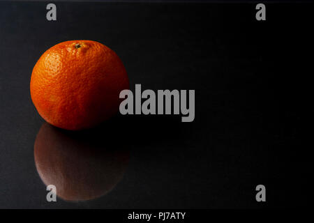 Mandarin Orange auf dunklen schwarzen Hintergrund mit Reflexion isoliert. Platz für Text. Citrus reticulata, auch Mandarin oder Mandarine bekannt, ist ein sma Stockfoto