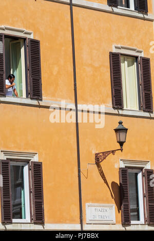 Ein Mann, Bürsten, seine Zähne, während Sie Ihren Blick von Fensterläden in Piazza di Trevi, Rom, Latium, Italien. Stockfoto