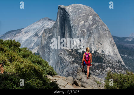 Eine weibliche Wanderer sieht auf den Half Dome, vom Glacier Point, Yosemite National Park, Kalifornien, USA Stockfoto