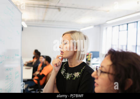 Fokussierte Geschäftsfrauen am Whiteboard im Büro Brainstorming Stockfoto