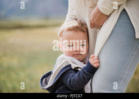 Liebevolle baby Sohn zur Mutter klammerte sich die Beine Stockfoto