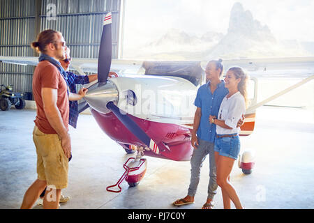 Freunde reden prop Flugzeug im Hangar Stockfoto