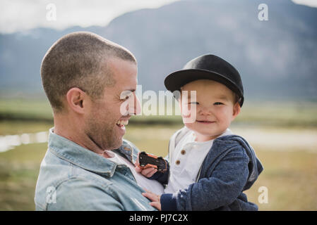 Vater Holding niedlich, Happy Baby Sohn gesucht an Kamera Stockfoto