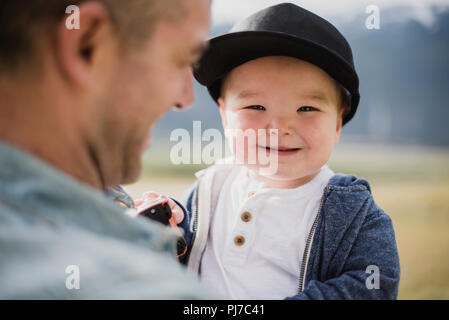 Portrait cute baby boy über Vater s Schulter Stockfoto