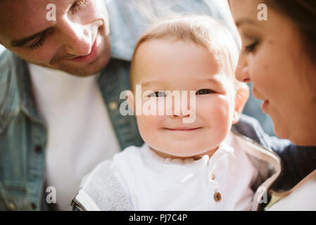 Eltern halten cute baby boy an Kamera suchen Stockfoto
