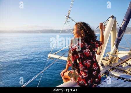 Ruhige junge Frau entspannende an sonnigen Katamaran, mit Blick auf das blaue Meer Stockfoto