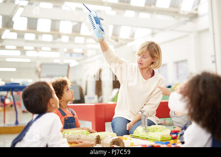 Neugierige Kinder beobachten Lehrer mit Spielzeug Flugzeug in Science Center Stockfoto