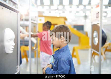 Neugierige Junge auf der Suche nach Gesicht in Science Center Stockfoto