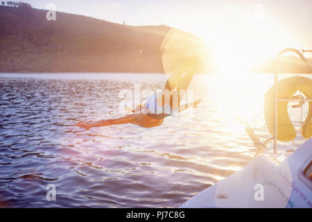 Frau springen Boot in sonnigen Ozean Stockfoto