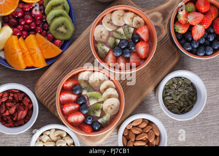 Smoothie mit Früchten und Beeren auf den grauen Holztisch, mit einer Vielzahl von Früchten und Nüssen herum, selektiver Fokus, Ansicht von oben Stockfoto