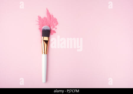 Make-up-Pinsel auf rosa Hintergrund mit bunten Farbpulver Stockfoto