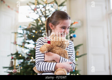 Glücklich umarmten Teddybär vor Weihnachtsbaum Stockfoto
