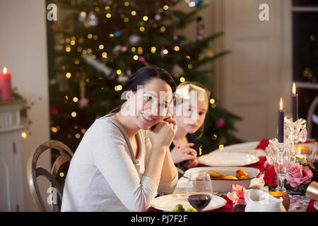 Portrait lächelnde Mutter und Tochter Weihnachten Abendessen bei Kerzenschein genießen. Stockfoto