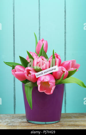 Guten Morgen Karte mit rosa Tulpen Purple Flower Pot mit Holz lackiert Blau im Hintergrund Stockfoto