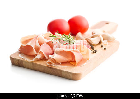 Italienische Prosciutto Crudo oder jamon mit Paprika, Tomaten, Knoblauch und Rosmarin auf Schneidebrett. Stockfoto