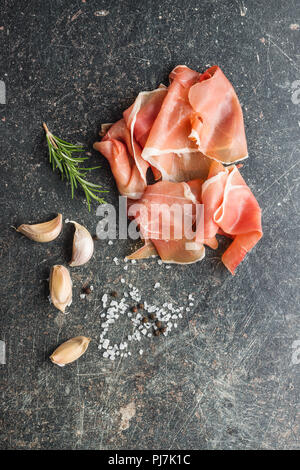 Italienische Prosciutto Crudo oder jamon mit Rosmarin, Knoblauch, Pfeffer und Salz. Stockfoto