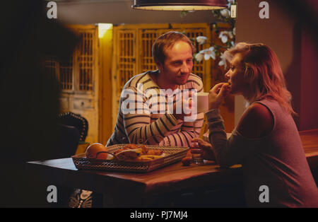 Paar Frau und Mann sitzen und trinken sie Tee oder Kaffee in der Küche zu Hause. Reden und zu Hause Ausruhen nach einem langen Tag Stockfoto