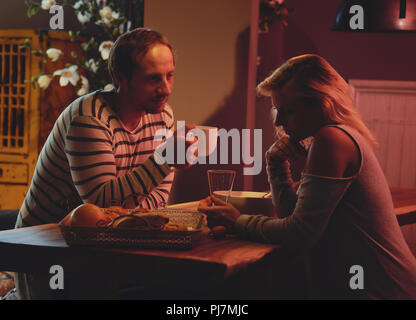 Paar Frau und Mann sitzen und trinken sie Tee oder Kaffee in der Küche zu Hause. Reden und zu Hause Ausruhen nach einem langen Tag Stockfoto