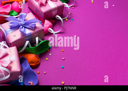 Festliche Hintergrund violett Material bunte Luftballons luftschlangen Konfetti drei Boxen Geschenk. Ansicht von oben flach kopieren Raum Stockfoto