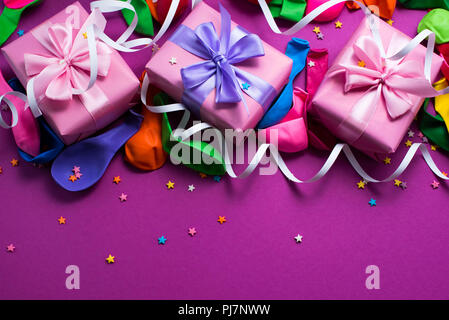 Festliche Hintergrund violett Material bunte Luftballons luftschlangen Konfetti drei Boxen Geschenk. Ansicht von oben flach kopieren Raum Stockfoto
