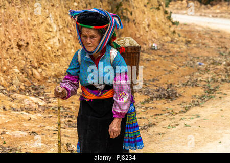 Ha Giang, Vietnam - am 18. März 2018: Die Frau, die zu Fuß auf einer staubigen Straße in der Nähe von landwirtschaftlichen Gebieten im Norden von Vietnam Stockfoto