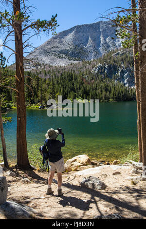 Eine Frau die Bilder mit Ihrem iPhone auf das Hilton Trail Seen in der östlichen Sierra Nevada, Kalifornien, USA Stockfoto