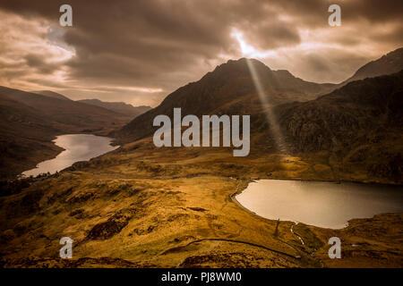 Ein einziger Sonnenstrahl durchdringt die Wolken über Llyn Idwal, Snowdonia, North Wales Stockfoto