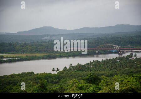 Ein Güterzug in Richtung Divar Island über die Brücke über den Fluss Mandovi gehen, als von der Kirche Unserer Lieben Frau von den Berg gesehen, Old Goa, Goa, Indien. Stockfoto