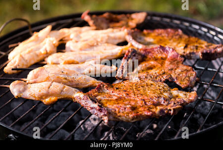 Die schweinekoteletts und hähnchenspieße am Grill zubereitet. Die Zubereitung von Fleisch und Grillen auf direkte Wärme in der Natur im Hinterhof BBQ-Picknick. Stockfoto