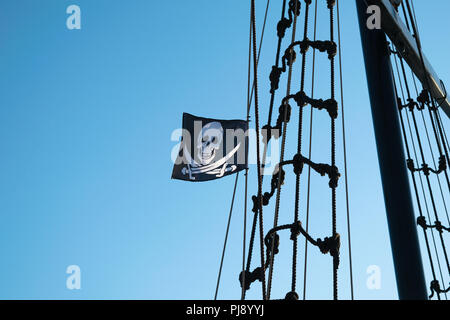 Angehobene Jolly Roger Piratenflagge auf einem Schiff mast. Stockfoto