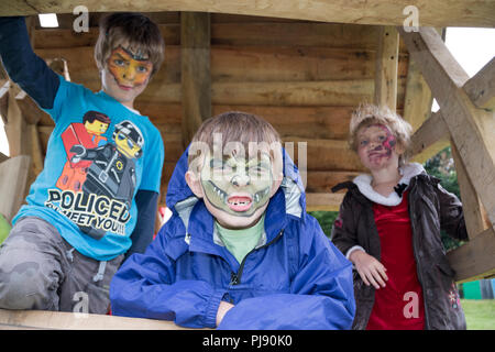 Drei Kinder stellen Ihre frisch lackierten Flächen - Junge mit Gesicht wie ein Krokodil zieht ein unheimlich Monster Gesicht malen zu zeigen Stockfoto