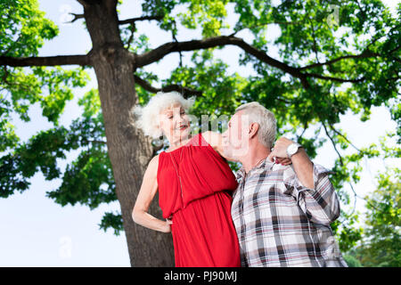 Stilvolle gealterte Frau das Tragen der roten Kleid und Accessoires zu ihrem Mann suchen Stockfoto