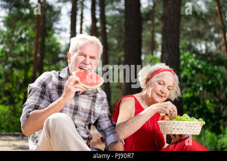 Ältere Frau und Mann essen leckere Früchte, während in Picknick Stockfoto