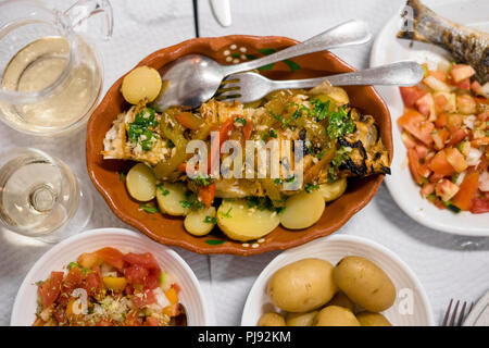 Traditionelle portugiesische goldener Fisch mit rotem und grünem Pfeffer mit gekochten Kartoffeln und Tomaten Salat serviert. Stockfoto