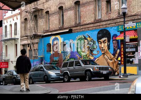 Ein Mann sieht auf der anderen Straßenseite bei einem Wandgemälde von Bruce Lee in der Chinatown von San Francisco, Kalifornien. Stockfoto