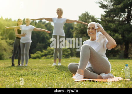 Freundliche ältere Frau Stirn abwischen nach dem Training Stockfoto
