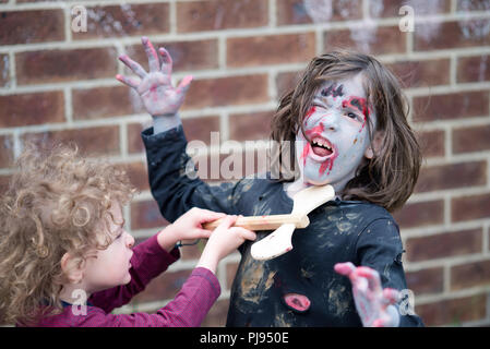 Junge mit Holz- ax Angriffe zombie Girl für Halloween Kinder zombie cosplay Stockfoto
