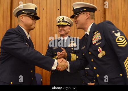 Coast Guard 13. Bezirk Master Chief Petty Officer Jason Wong, auf-kommenden command Master Chief, schüttelt Hände mit Master Chief Sean McPhilamy, die Ausrückenden command Master Chief nach Linderung McPhilamy während eines Change-of-watch Zeremonie in Seattle, 9. Juli 2018 statt. Wong und McPhilamy schüttelte Hände nach Abschluss der offiziellen Übertragung der Autorität. Us-Küstenwache Stockfoto