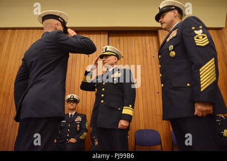 Coast Guard 13. Bezirk Master Chief Petty Officer Ryan Hooper, auf-kommenden Reserve Command Master Chief, begrüßt der Adm. David Throop, Commander, nach Hooper übernahm die Aufgaben der Reserve Bezirk command Master Chief während eines Change-of-watch Zeremonie in Seattle, 9. Juli 2018 statt. Hoopers salute in Teil abgeschlossen Die offizielle Übernahme der Verantwortung von Timothy Bart, die Ausrückenden Reserve Command Master Chief. Us-Küstenwache Stockfoto