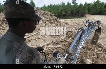 Us Air Force Senior Airman Matthew Williams mit Die 166 Bauingenieur Squadron, California Air National Guard, betreibt eine Baggerlader zu trennt Schmutz aus Holz verbrannt wird, als Teil der Phase eins Bau von Camp Kamassa in Crystal Springs, Mississippi, 9. Juli 2018. Camp Kamassa werden die Mitgliedstaaten erste vollständig behindertengerecht, ganzjährig Camp für Kinder und Erwachsene mit besonderen Bedürfnissen, die auf 326 Hektar von der Abteilung für Innovative's Defence Readiness Training Programm spearheaded gebaut wird. Stockfoto