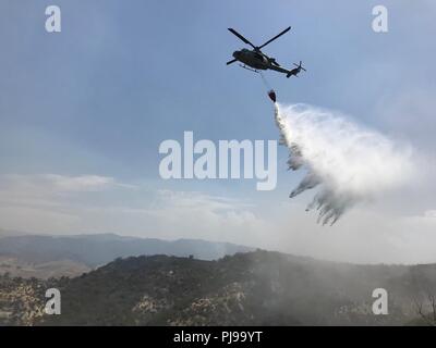 Marines mit Marine Light Attack Helicopter Squadron (HMLA) 267 und HMLA-169, Marine Aircraft Group (MAG) 39, 3. Marine Flugzeugflügel, Durchführung Wassereimer Tropfen über Feuerwehr zur Unterstützung der Löscharbeiten bei Marine Corps Base Camp Pendleton, Calif., Juli 6. Die "Pendleton Komplex", bestehend aus drei separaten Brände, brannte fast 2.000 Hektar. In allen sechs Flugzeugen vom 3. MAW durchgeführt fast 250 Wassertropfen über zwei separate Brände in 30 Stunden. Stockfoto