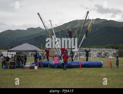 Kinder Bounce auf dem Bungee Trampoline während des 3. jährlichen Sommerfest von der 673 d Force Support Squadron bei Joint Base Elmendorf-Richardson, Alaska, 8. Juli 2018 veranstaltet. Die Veranstaltung ist offen für Jedermann mit Base Access und kostenlose Aktivitäten wie Karneval Fahrten, ein Streichelzoo, Kinderschminken, ein Bungee Trampolin, und Karneval Spiele. Stockfoto