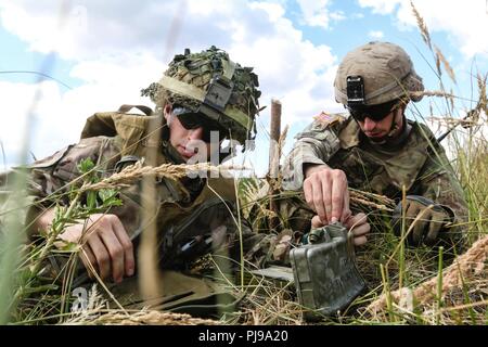 U.S. Army Staff Sgt. Robert Moore (rechts), mit der 1. Staffel, 2. Reiterregiment, hilft bei der britischen Armee LT. Tom Chapman (links), die 1. Die Queen's Dragoon Guards zugewiesen, bis M18 A1 Claymore Mine während eines multinationalen claymore Ausbildung Übung mit Battle Group Polen Bemowo Piskie, Polen am 10. Juli 2018 eingestellt. Battle Group Polen ist ein einzigartiges, multinationale Koalition von USA, Großbritannien, Kroatischen und rumänischen Soldaten, die mit der polnischen 15 mechanisierte Brigade als Abschreckung Kraft zur Unterstützung des NATO-Enhanced vorwärts Präsenz dienen. Stockfoto